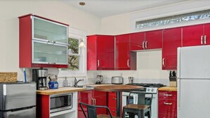 A compact kitchen with red cabinets, a stainless steel refrigerator, a microwave, a stove, and a sink. - Steps to SoCo, Mins to Zilker | Quiet Pet-Friendly Casita w Grill + Workspace (Austin)
