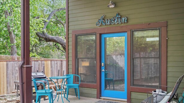 A house with a blue door, a covered patio with turquoise chairs, and a grill. - Steps to SoCo, Mins to Zilker | Quiet Pet-Friendly Casita w Grill + Workspace (Austin)