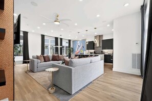 Ein modernes Wohnzimmer mit einem grauen Sofa, einem kleinen runden Couchtisch und einem Deckenventilator.
