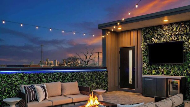 An outdoor seating area with a fire feature, a flat-screen TV, and a city view. - Lux Home - 8 Beds | 3.5 Bath | Firepit Sleeps 12! (Nashville)