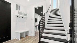 A staircase with black railings leading to a landing with white shelves and a bench. - Lux Home - 8 Beds | 3.5 Bath | Firepit Sleeps 12! (Nashville)