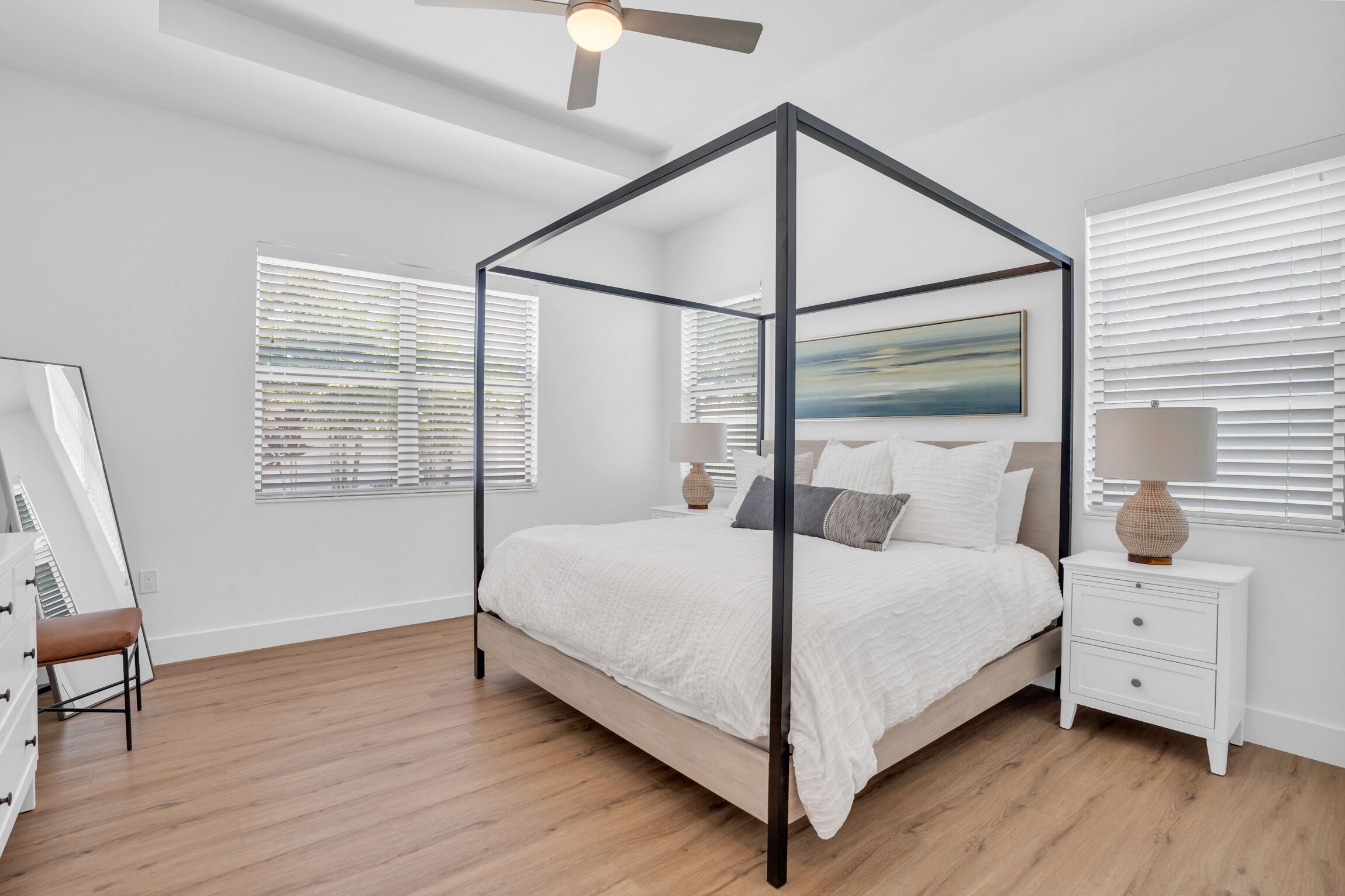 Un dormitorio con cama con dosel, una mesita de noche con lámpara y un cuadro en la pared.