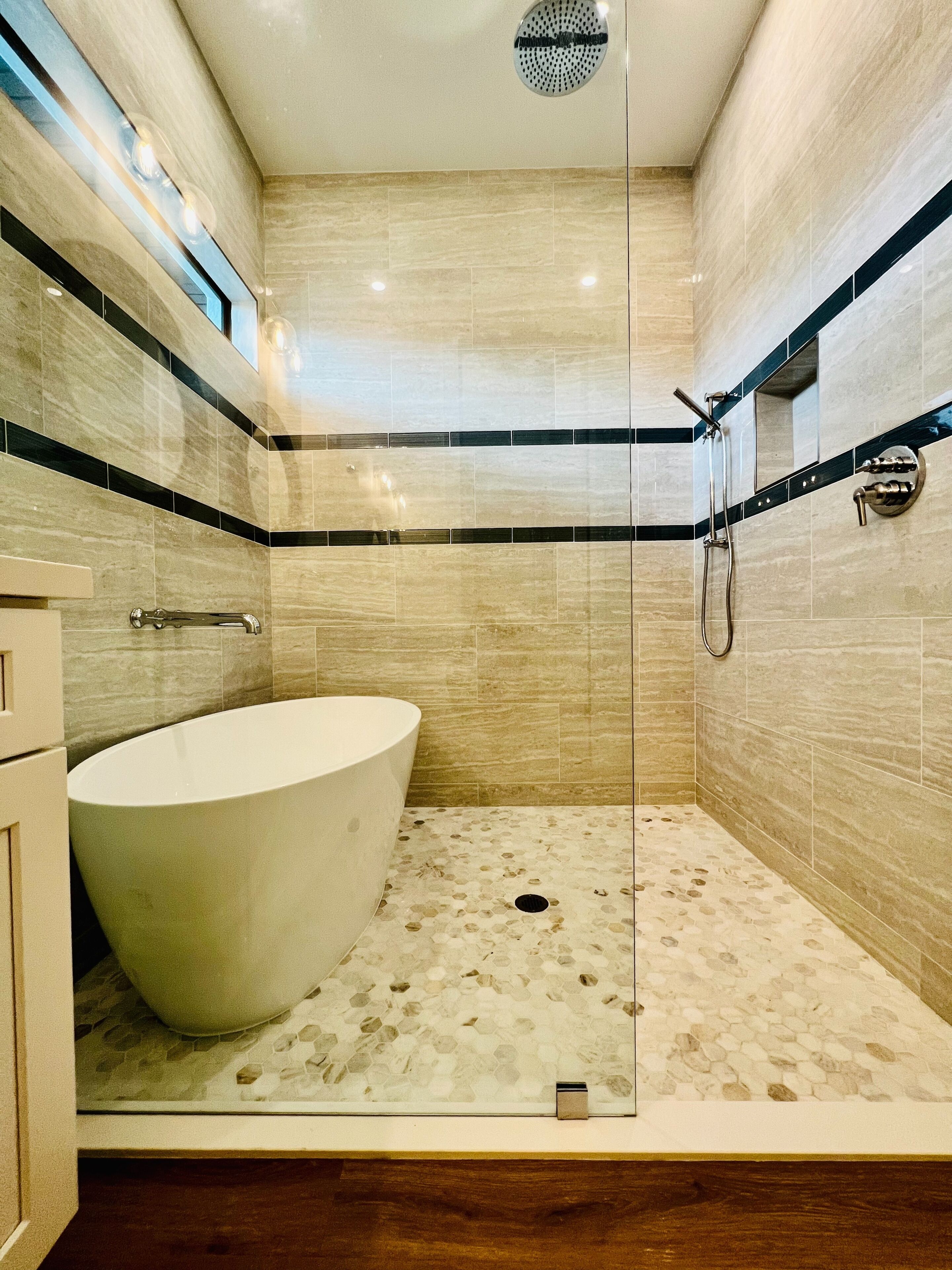 A bathroom with a freestanding bathtub, a glass-enclosed shower, and a tiled floor.