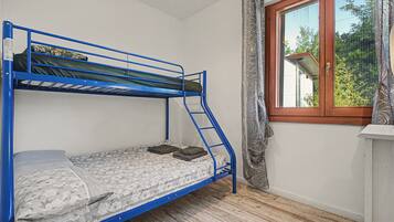 Un letto a castello con materasso a fiori, una finestra vista su del verde e un pavimento in legno.
