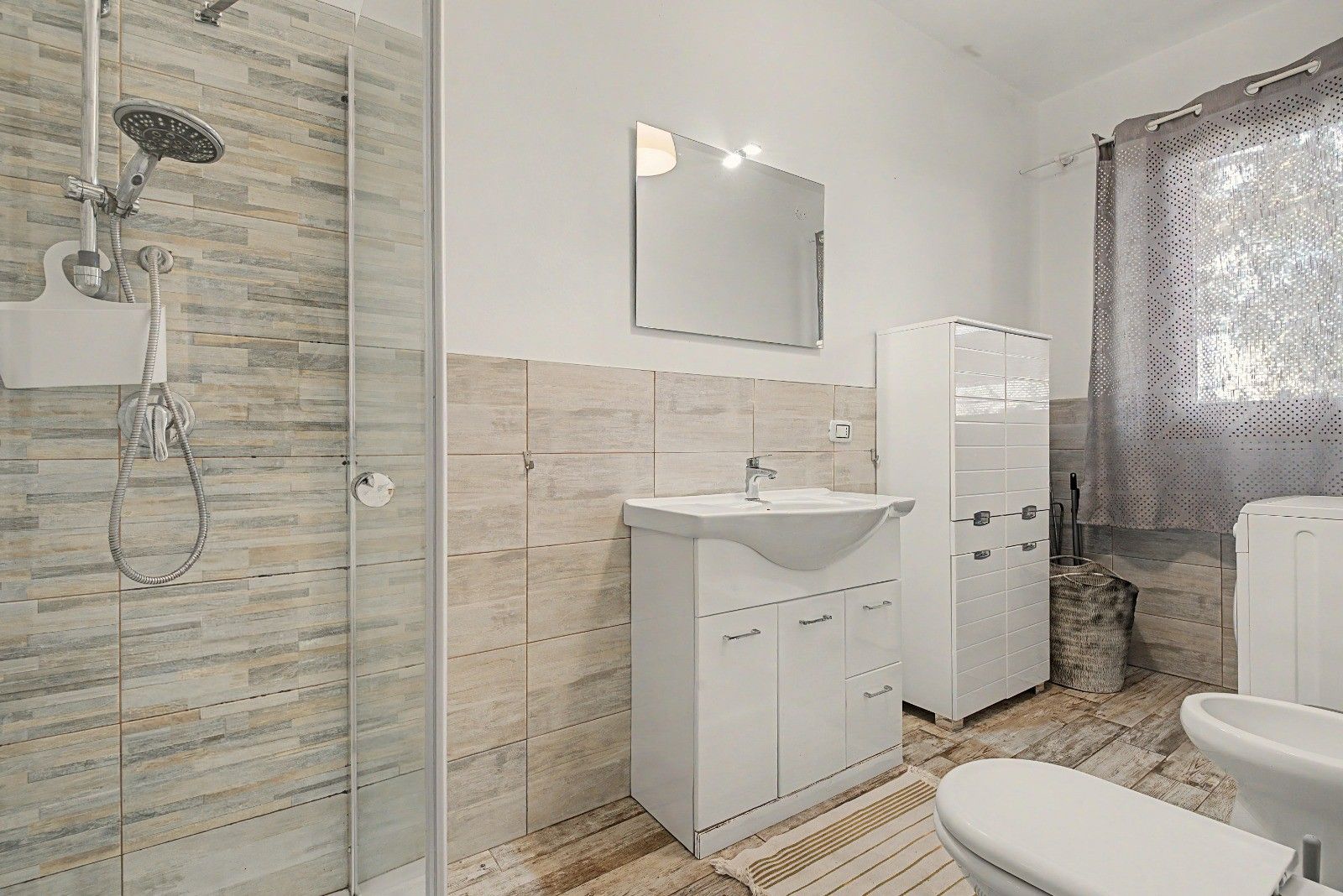 A modern bathroom with a glass shower enclosure, a white sink, and a toilet.