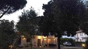 Ein Haus mit überdachter Terrasse, einer Treppe und einem geparkten Auto davor.