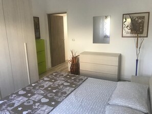 A bedroom with a bed, a dresser, a mirror, and a door leading to another room.