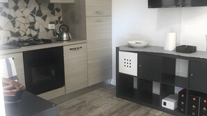 Eine moderne Küche mit Gasherd, Backofen und einem flachbildfernseher, der über der Arbeitsplatte angebracht ist.