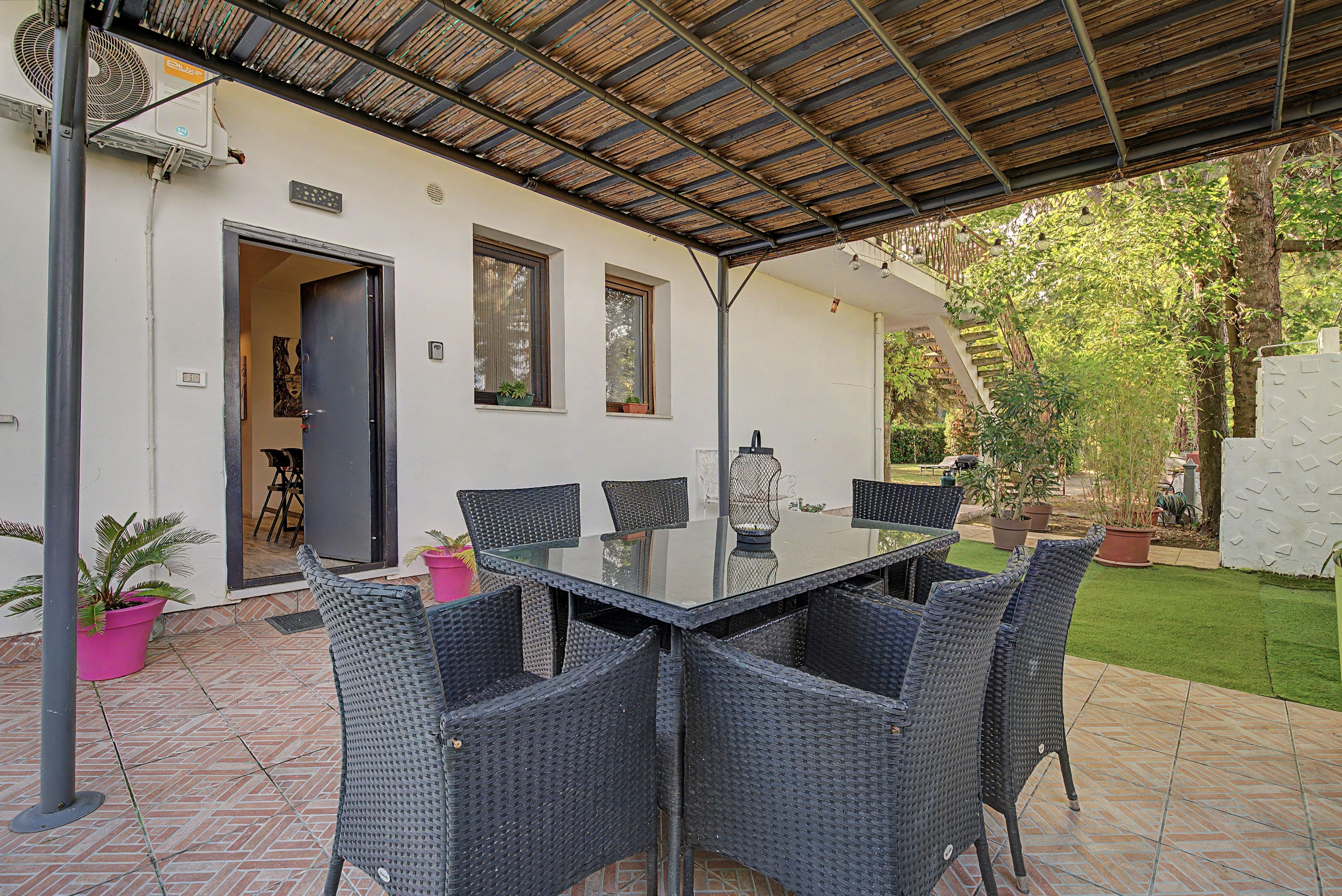 Eine Terrassenanlage mit Tisch und Stühlen, einem überdachten Bereich und einem Garten.
