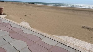 A beach with a clear sky, a sandy shore, and a tiled walkway.