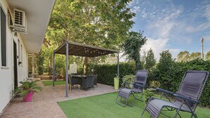 A patio with a pergola, outdoor furniture, and a small lawn.