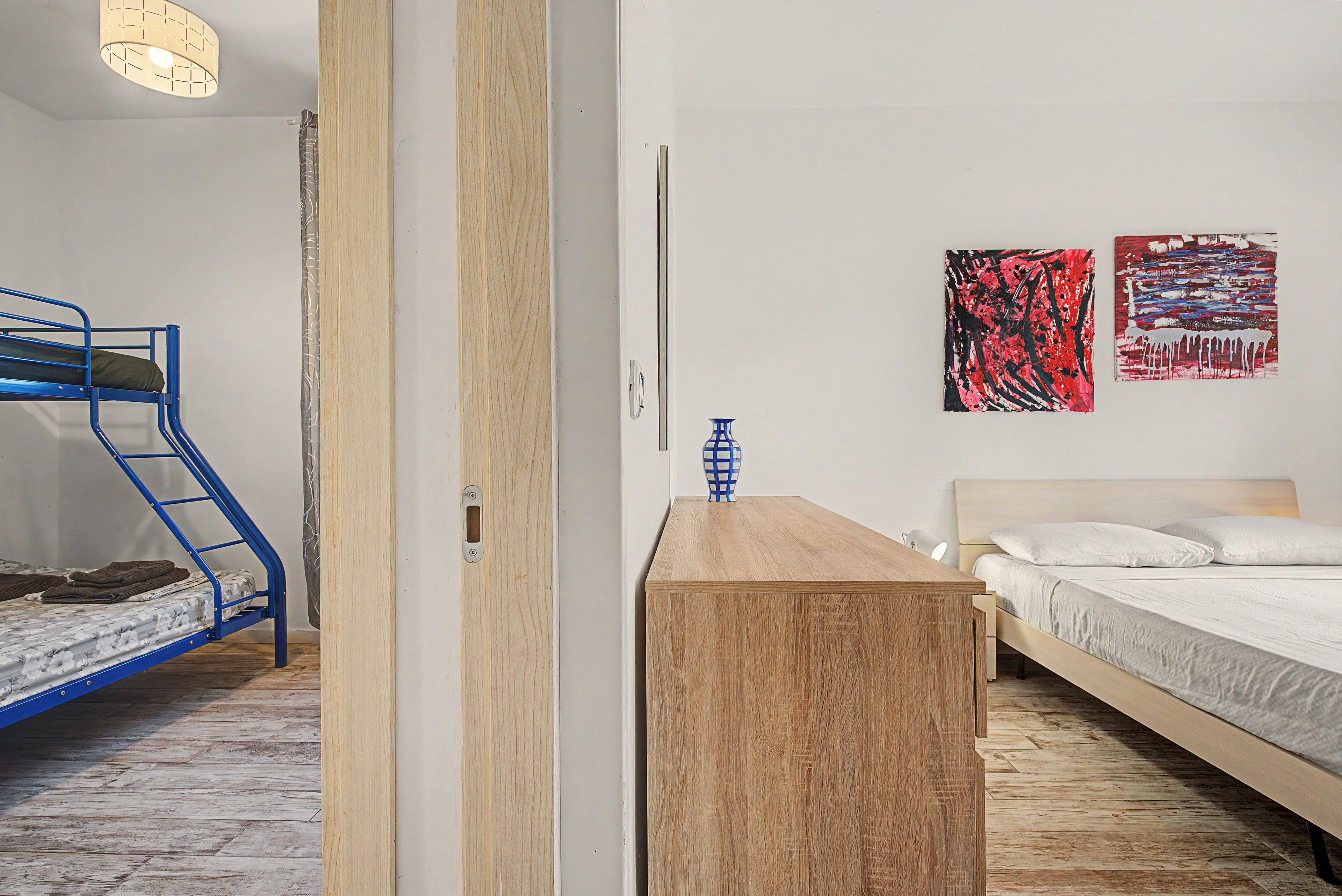 Une chambre avec un lit superposé, un bureau en bois et deux tableaux accrochés au mur.