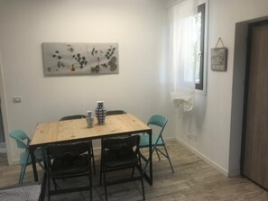 A dining area with a wooden table, four chairs, a vase, and a wall-mounted abstract painting.
