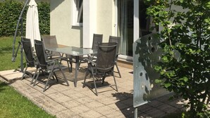 Een huis met een terras, een schotelantenne en een groot raam.