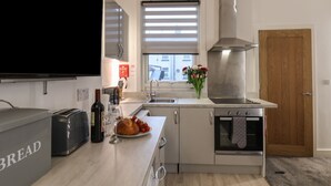 Eine moderne Küche mit Einbauofen, Spüle und einem großen Fenster mit Jalousien.