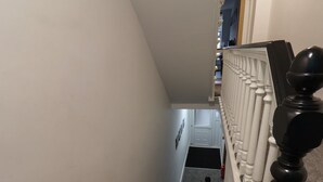 Eine Treppe mit weißen Wangen und einem schwarzen Geländer, die zu einer Zwischenebene mit einer Tür und einem Feuerlöscher führt.