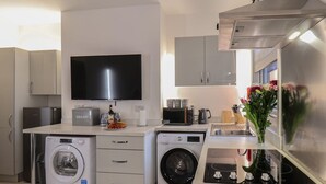 Eine kompakte Küche mit Waschmaschine, Mikrowelle, Toaster und Spüle.