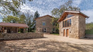 Un bâtiment en pierre doté d’un patio couvert et d’une autre construction en pierre, séparée, avec une porte en bois.