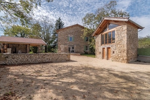 Un bĂątiment en pierre dotĂ© dâun patio couvert et dâune autre construction en pierre, sĂ©parĂ©e, avec une porte en bois.