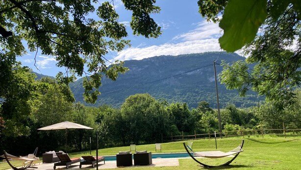 Un espace extérieur verdoyant avec une piscine, des chaises longues et un hamac.