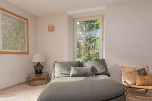 Un dormitorio con cama, ventana con vistas a árboles, mapa en la pared y lámpara en una mesita de noche.