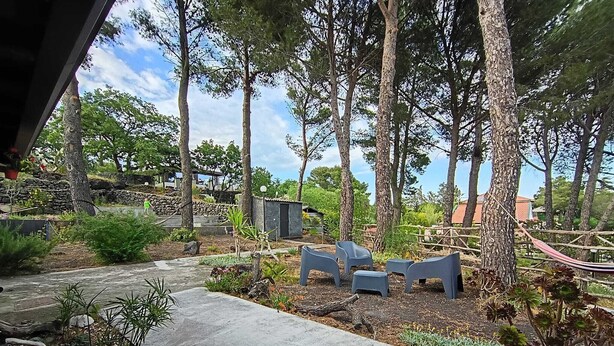 A garden with a paved pathway, seating area, and potted plants. - Etna Country Home!  A relaxing retreat surrounded by nature (Nicolosi)