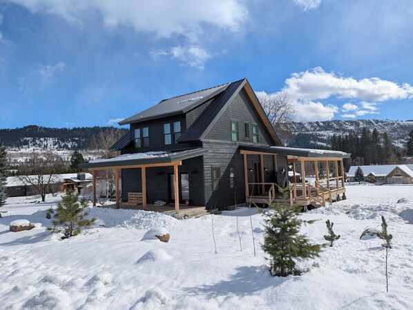 Una casa moderna con una amplia terraza, rodeada de nieve y montañas.