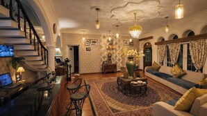 A spacious living room with a large sofa, a coffee table, and a staircase. - Heritage Rose Inn - Dal Lake (Srinagar)