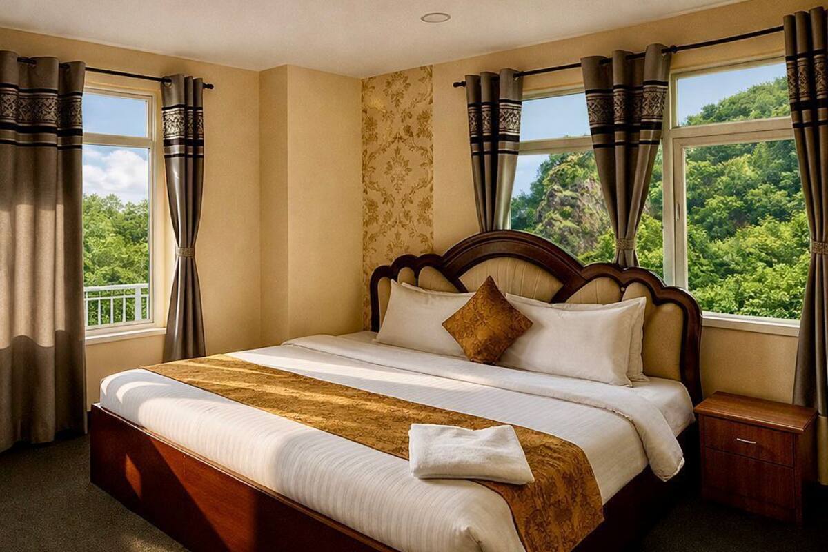 A large bed with a wooden headboard, a bedside table, and curtains.