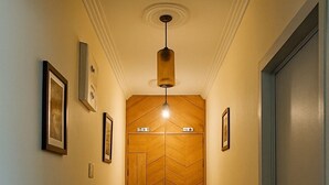 A hallway with a checkered floor, wooden paneling on the walls, framed pictures, and a door on the right. - Heritage Rose Inn - Dal Lake (Srinagar)