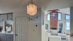 A modern kitchen with white cabinets, a decorative mirror, and a chandelier. - The Odyssey - Waterfront with Dock + Boat Lift + NH Village Beach Club Member! (Kill Devil Hills)