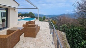 Un patio con mobiliario de mimbre, una piscina y vistas a montañas.