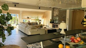 A modern living room with a sofa, dining table, and kitchen area. - Villa for 7 guests with private pool and hot tub near Cannes (Fréjus)