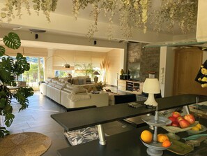 Ein modernes Wohnzimmer mit Sofa, Esstisch und Küchenbereich.