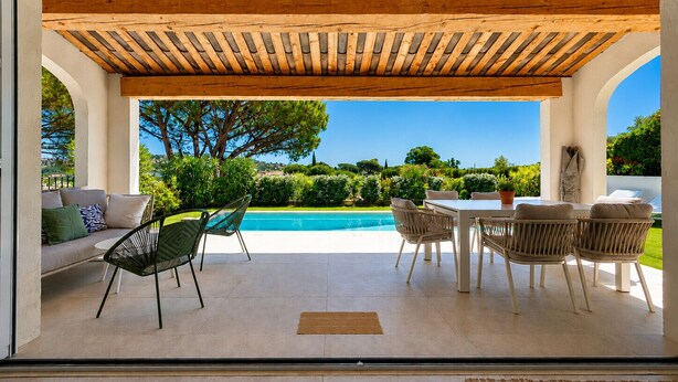 Une terrasse extérieure couverte avec une piscine, un espace salon et une vue sur le paysage.