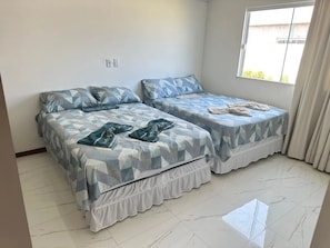 A room with two beds, a window with curtains, and a tiled floor.