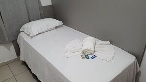 A single bed with a grey headboard, white bedding, and a towel with toiletries. - Apartment for you and your privacy with private bathroom, Lucas do Rio Verde Hotel (Lucas do Rio Verde)