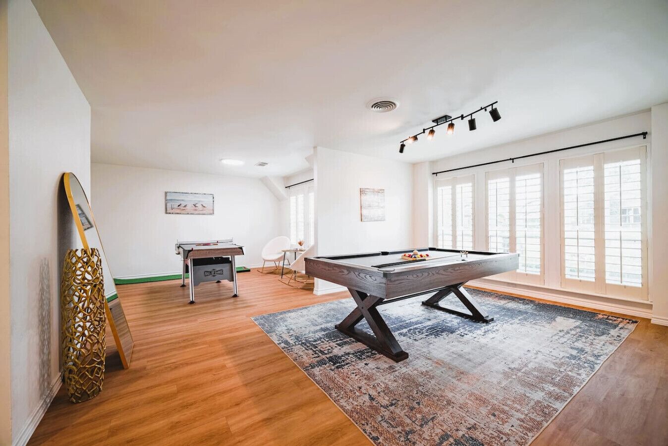 Une pièce spacieuse équipée d’une table de billard, d’une table de ping-pong et d’une table de jeu de flipper.