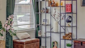 Una sala de estar con un sofá, una mesa de centro, una estantería y una ventana con cortinas.
