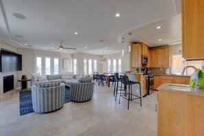 A spacious living area with a sofa set, a television, and a kitchen with wooden cabinets and a sink. - South Mission Sand & Surf Retreat with AC & 3 Car Garage! (San Diego)