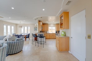 A spacious living area with a dining table, kitchen, and a door leading to another room. - South Mission Sand & Surf Retreat with AC & 3 Car Garage! (San Diego)