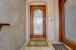 A hallway with a wooden door, a doormat, and a textured wall. - South Mission Sand & Surf Retreat with AC & 3 Car Garage! (San Diego)
