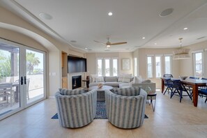 Ein geräumiges Wohnzimmer mit Kamin, Deckenventilator und Essbereich mit Tisch und Stühlen.