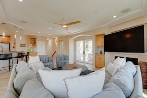 A modern living room with a sofa set, a coffee table, and a flat-screen TV mounted above a fireplace. - South Mission Sand & Surf Retreat with AC & 3 Car Garage! (San Diego)