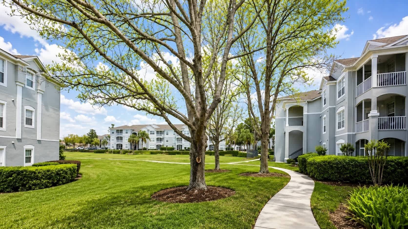 A residential building with a central lawn, a pathway, and multiple balconies.