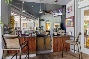 A bar area with a counter, chairs, and a television screen. - Windsor Palms Condo - Resort Pool, Hot Tub- Near Disney (Kissimmee)