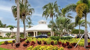 A building with a white roof and a central dome, surrounded by palm trees and a landscaped garden with yellow and red flowers. - Windsor Palms Condo - Resort Pool, Hot Tub- Near Disney (Kissimmee)