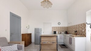 Een knus leefruimte met een kitchenette, een bank, een houten salontafel en een eettafel.
