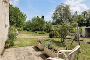 Une cour avec un banc en pierre, des jardinières et une vue sur un bâtiment en arrière-plan.