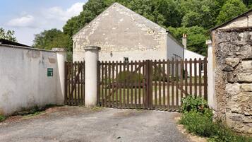 A rustic building with a stone facade, a wooden gate, and a gravel driveway.